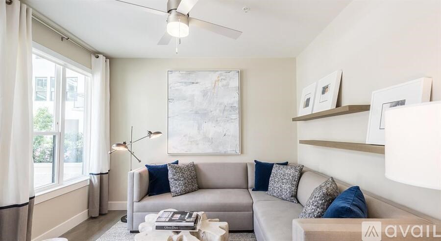 A living room with a grey couch, a white coffee table, and a large painting on the wall.