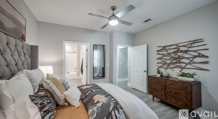 A bedroom with a large bed and a wooden dresser.