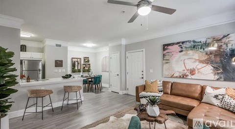 A living room with a brown couch and a painting on the wall.