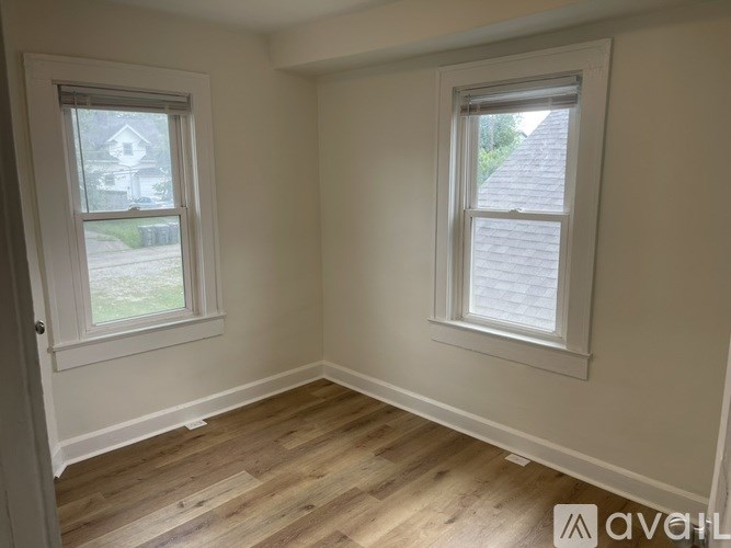 A room with two windows and wooden floors.