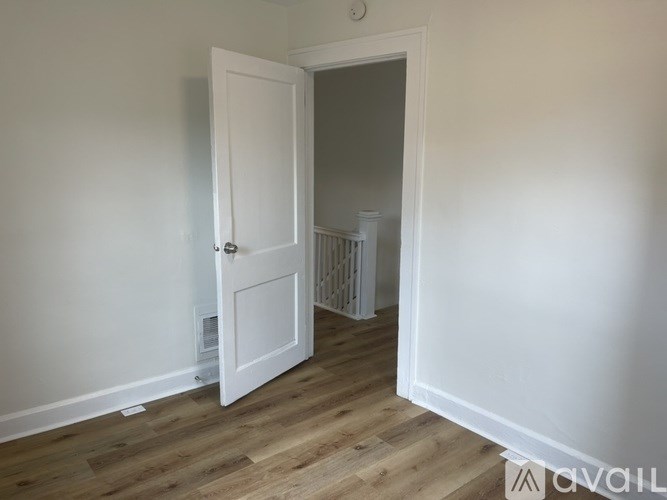 A room with a white door and a window on the right side.