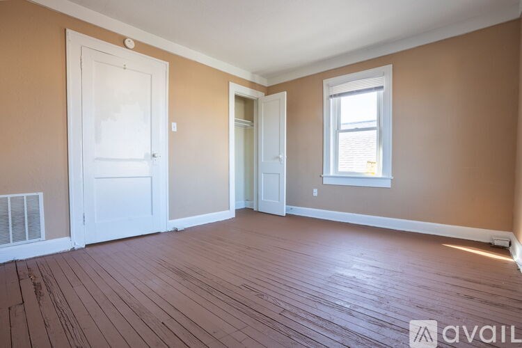 A room with wooden flooring and a window with white trim.