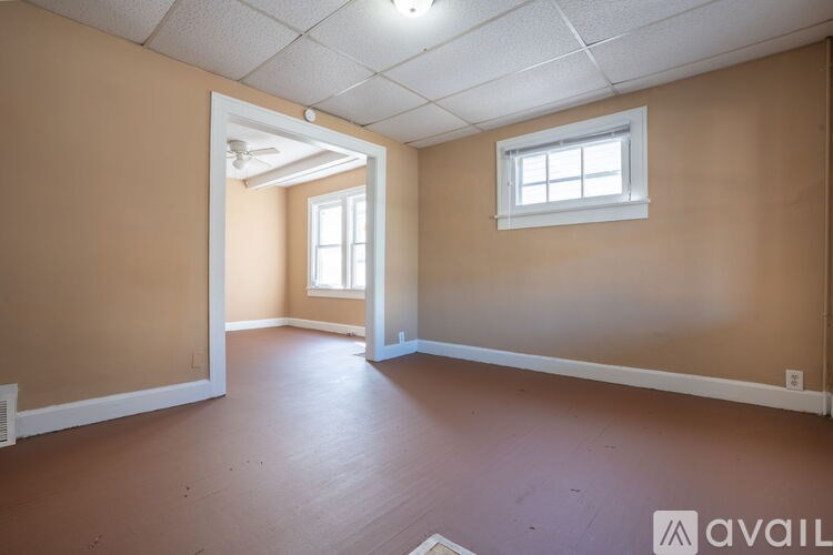 A room with a window and a doorway leading to another room.