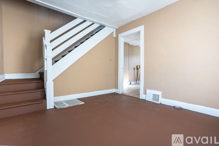 A room with a staircase and a doorway leading to another room.