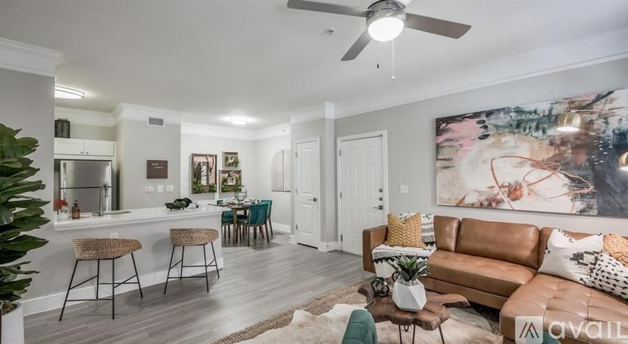 A living room with a brown couch and a painting on the wall.