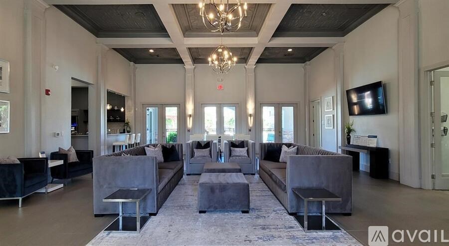 A spacious living room with grey furniture and a chandelier.