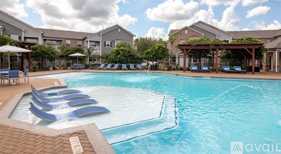 A large swimming pool with lounge chairs and umbrellas in front of apartment buildings.