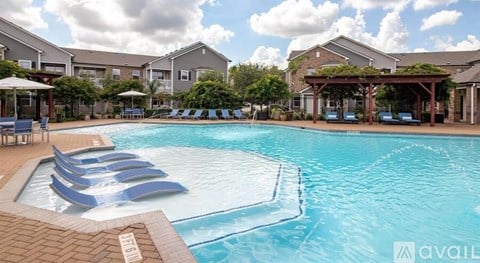 A large swimming pool with lounge chairs and umbrellas in front of apartment buildings.