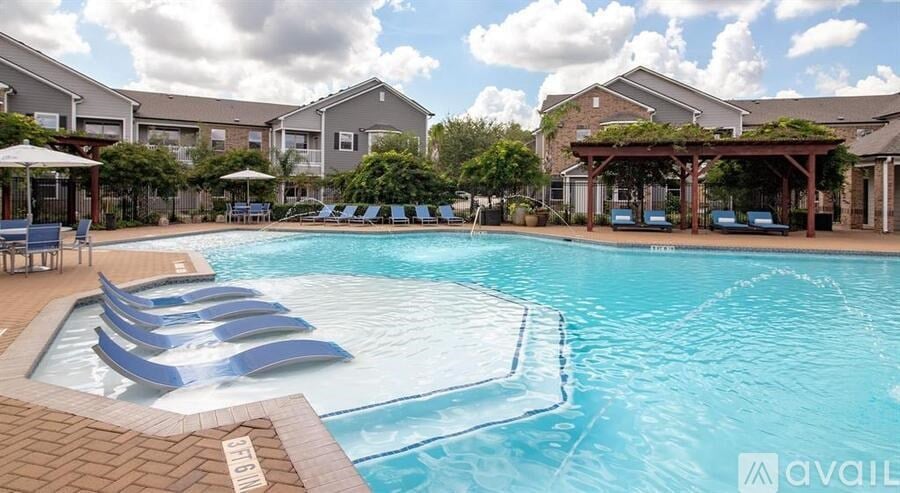 A large swimming pool with lounge chairs and umbrellas in front of apartment buildings.