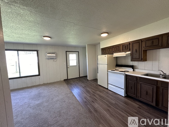 A kitchen with a white fridge, sink, and cabinets.