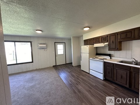 A kitchen with a white fridge, sink, and cabinets.