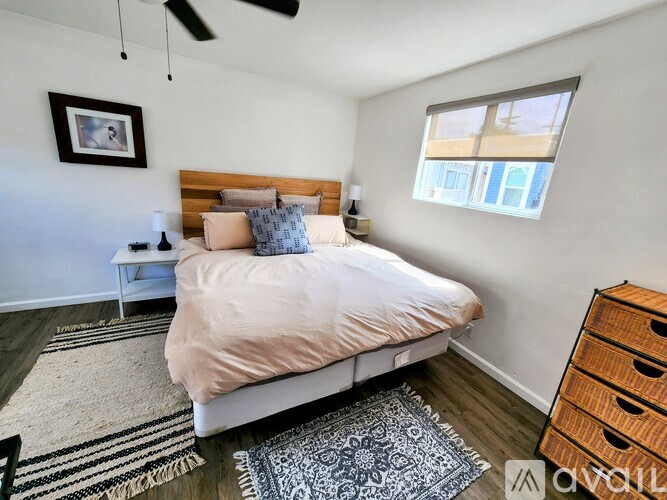 A bedroom with a large bed, a ceiling fan, and a window with a view of a building outside.