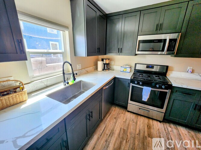 A kitchen with dark green cabinets and a stainless steel oven.