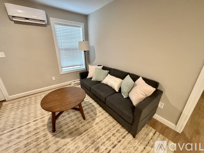 A living room with a grey couch, a wooden table, and a carpet.