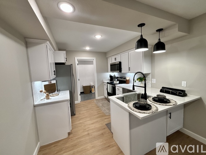 A kitchen with white cabinets and a wooden floor.