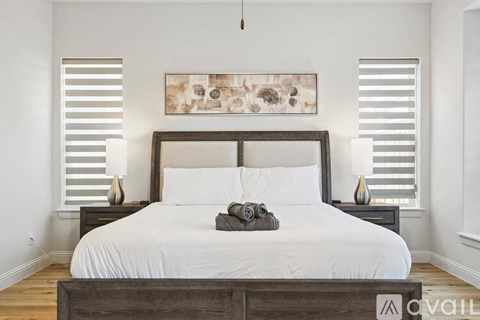 A bedroom with a large bed and a painting above it.