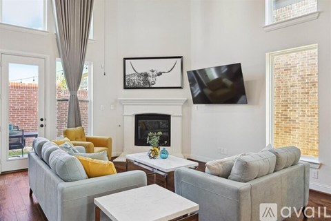 A living room with a grey couch, a white coffee table, and a fireplace with a painting above it.