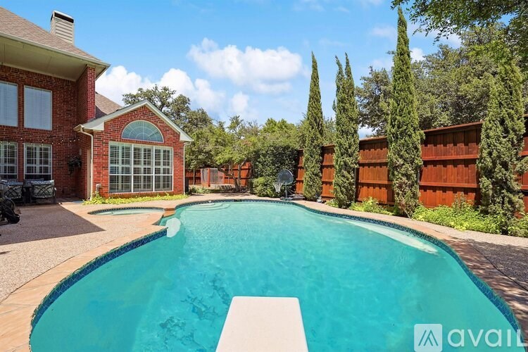 A large swimming pool in a backyard with a house and trees in the background.