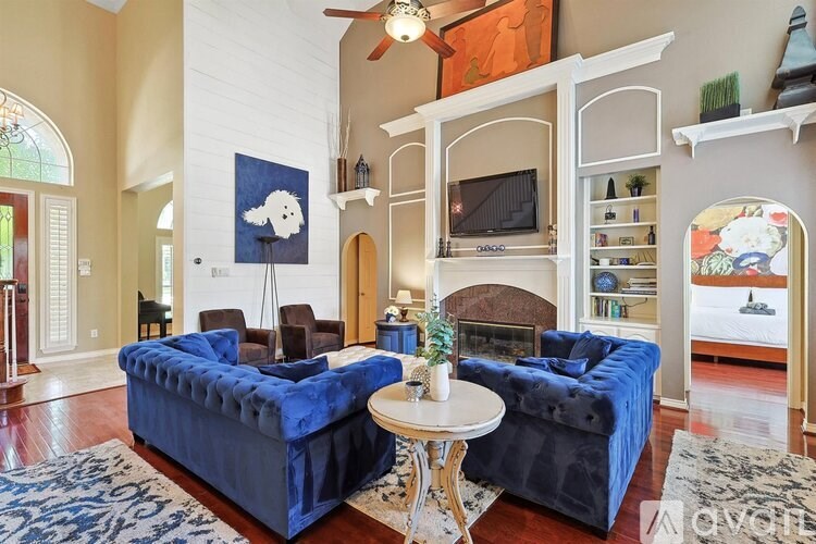A living room with a blue couch and a white ceiling fan.