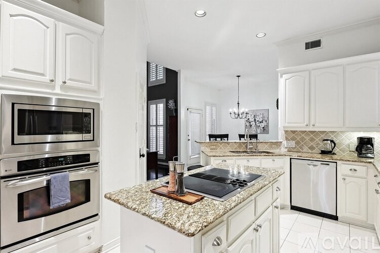 A kitchen with white cabinets and a granite countertop.