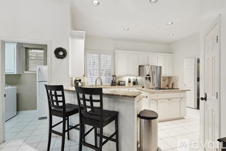 A kitchen with white cabinets and a black chair.