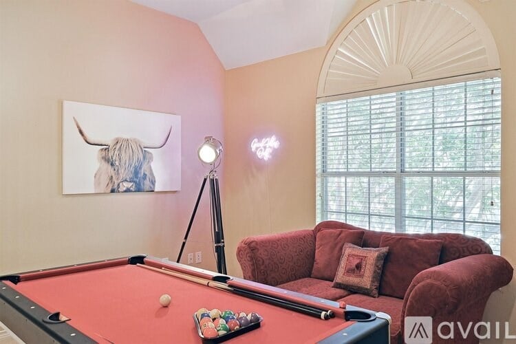 A pool table with a red cloth and a pool stick on it.