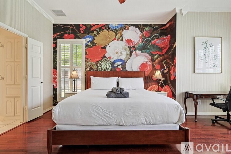 A bedroom with a large bed and a floral wallpaper.