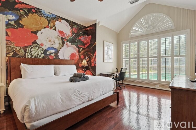 A bedroom with a large bed and a floral wallpaper.