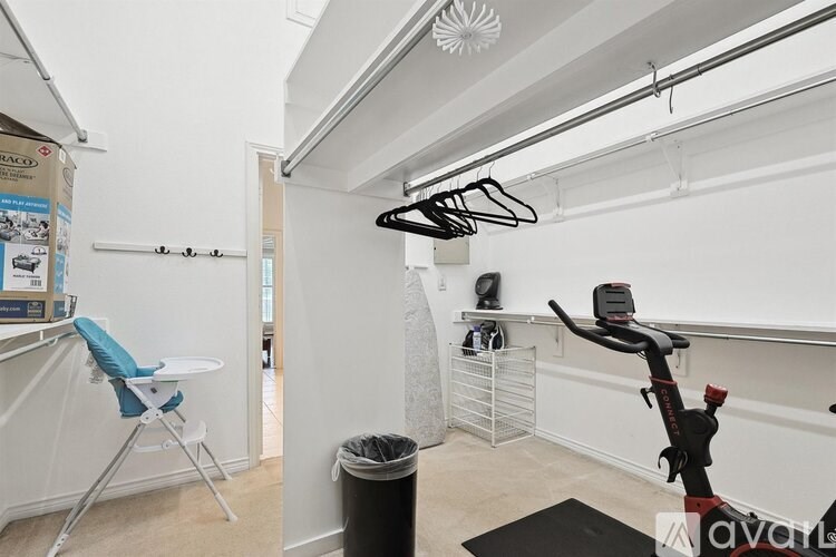 A room with a white ironing board and a black ironing board cover.