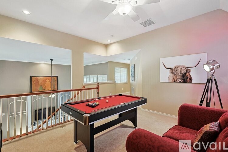 A pool table in a room with a red chair and a painting of a bull on the wall.