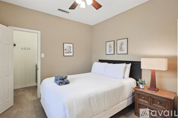 A bedroom with a bed, nightstand, and two pictures on the wall.