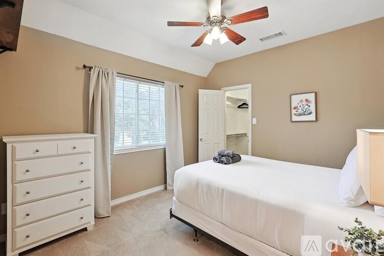 A bedroom with a bed, dresser, and window.