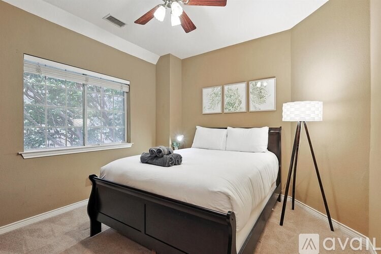 A bedroom with a bed, a window, a ceiling fan, and a floor lamp.