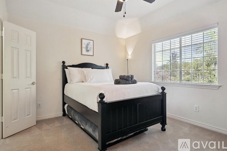 A bedroom with a black bed and a ceiling fan.