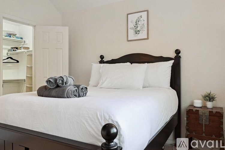 A bedroom with a white bed and a wooden headboard.
