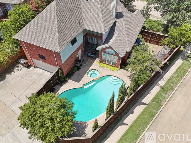 A house with a red brick exterior and a turquoise pool in the backyard.