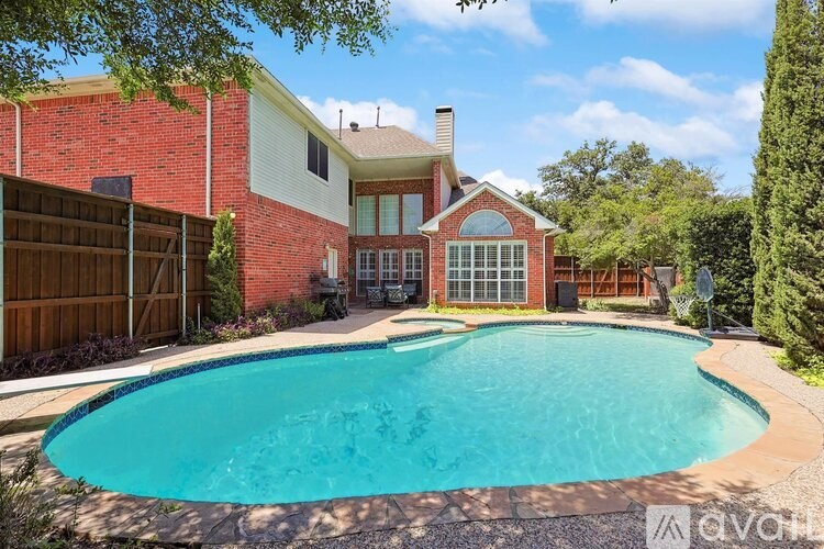 A house with a red brick exterior and a blue pool in the backyard.