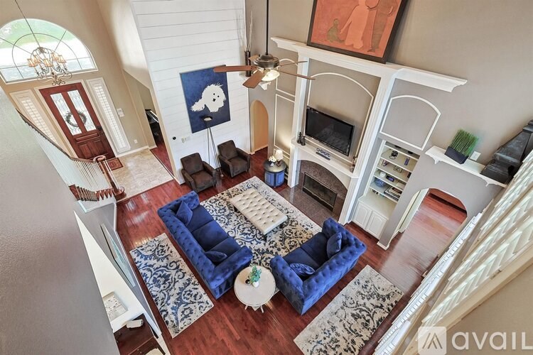 A living room with a blue couch and a white fireplace.