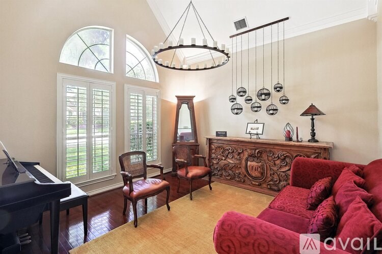 A living room with a piano, a chair, a sofa and a lamp.