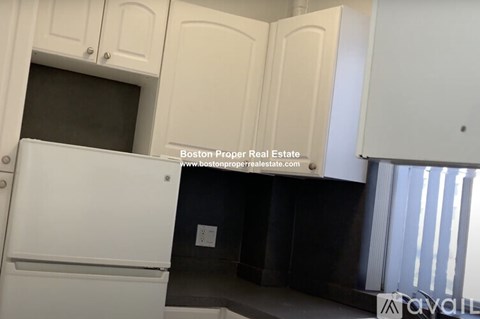 A kitchen with white cabinets and a white refrigerator.