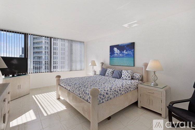 A bedroom with a large bed and a painting of a beach scene on the wall.