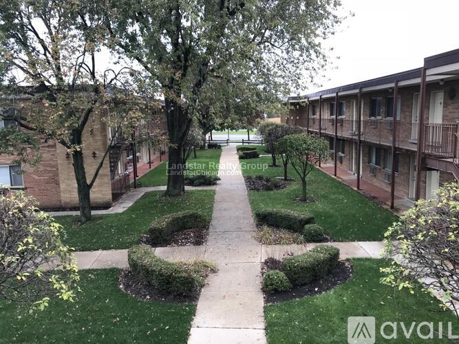 A courtyard with a pathway and greenery in front of apartment buildings.