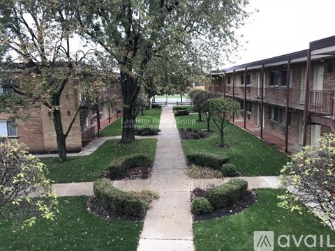A courtyard with a pathway and greenery in front of apartment buildings.