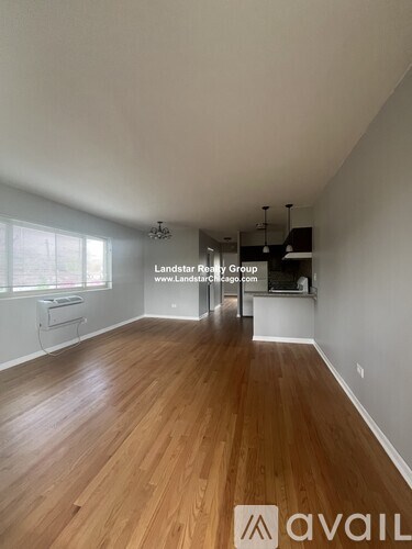 A room with wooden flooring and a window with blinds.