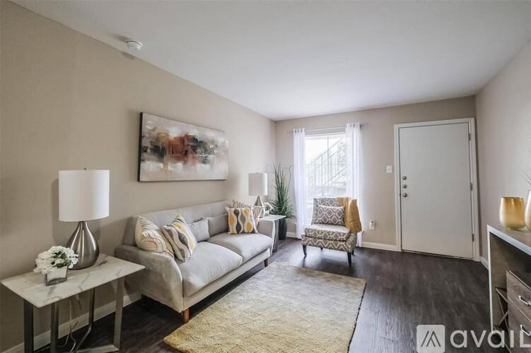 A living room with a grey couch, a white table, and a painting on the wall.