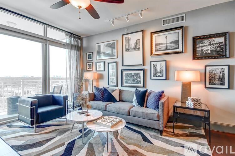 A living room with a grey couch, a blue chair, a coffee table, and pictures on the wall.