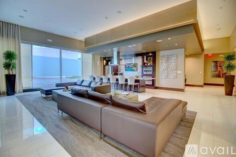 A spacious living room with a large sectional sofa and a view of the outdoors through the windows.