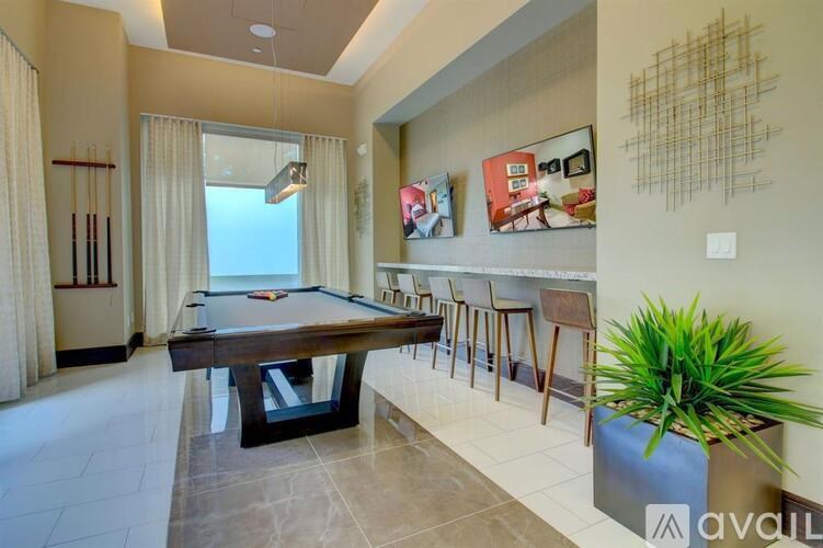 A pool table is surrounded by chairs in a room.