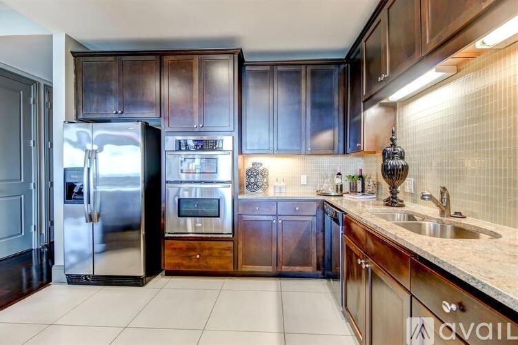 A kitchen with dark wood cabinets and a stainless steel refrigerator.