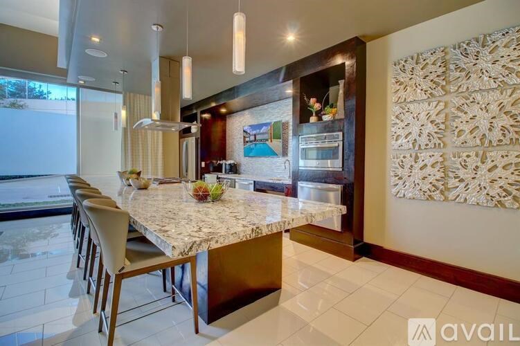 A kitchen with a marble table and chairs with a view of the outside.